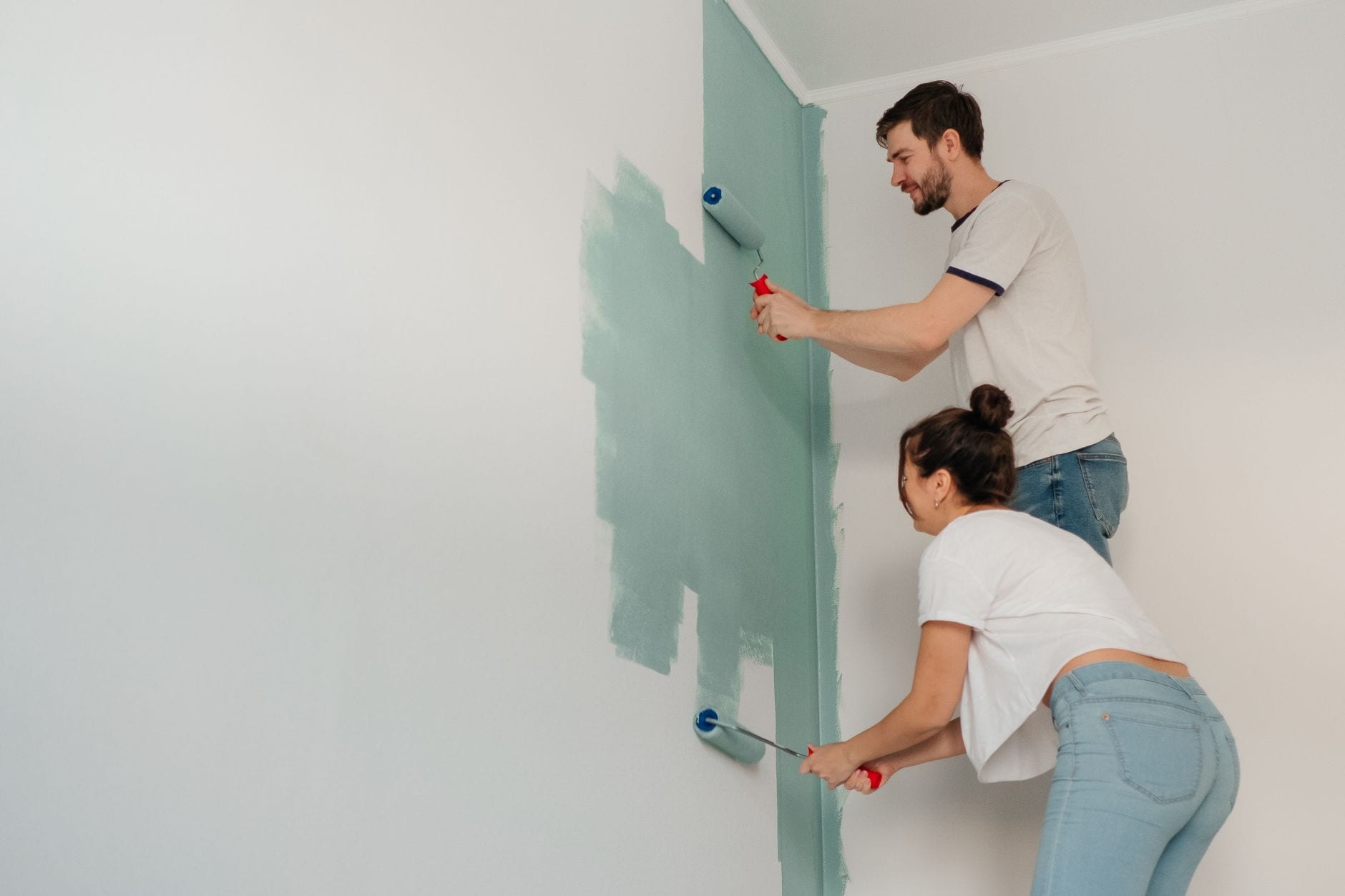 Painter rolling paint onto a large feature wall