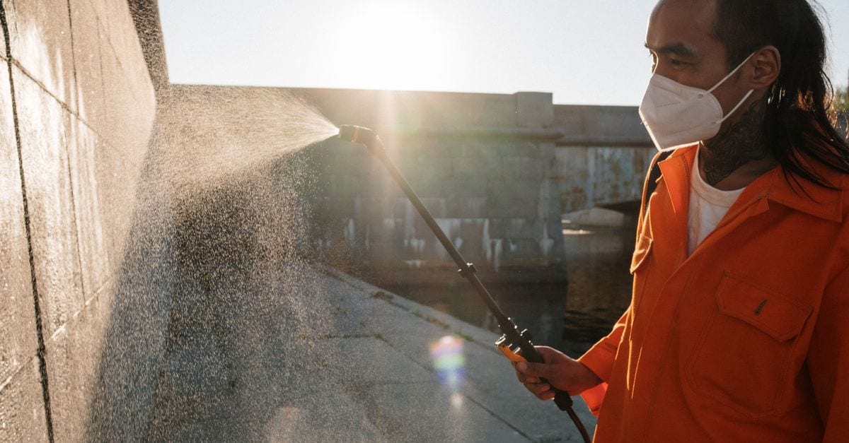 Tradesperson applying sealer to a concrete footpath