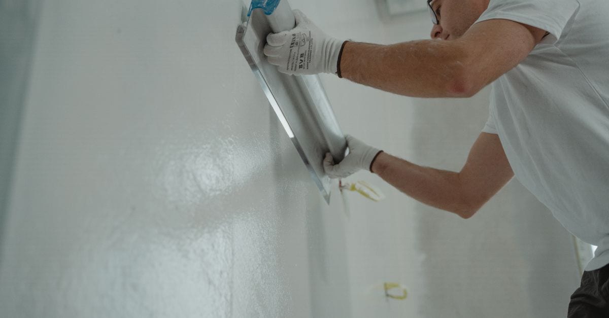Tradesperson applying an even coat of paint to an interior wall